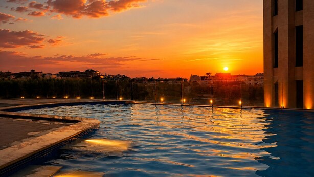 A swimming pool with a sunset view, a building with vertical lines, and a distant cityscape.