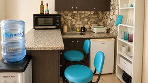 A compact kitchen with a water dispenser, microwave, sink, and a small refrigerator.