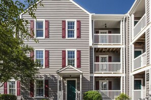 A multi-story building with a central entrance, balconies, and a porch.