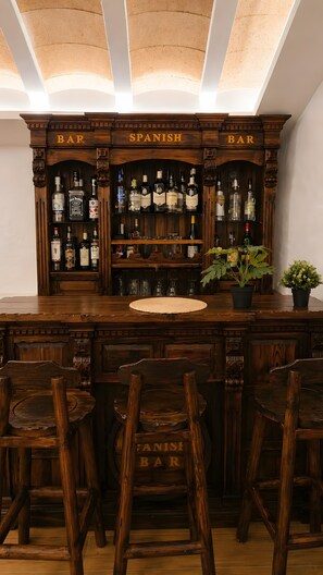 A bar with wooden shelves, two labeled as 'BAR' and 'SPANISH BAR,' and a central round table. - Country House 'Burraca Oasis en Cártama' with Mountain View, Private Pool and Terrace (Cártama)