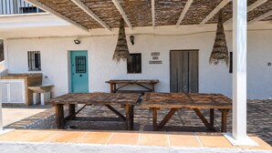 A covered outdoor area with two wooden tables, a blue door, and a sign reading 'CINQ DE JUINEX'. - Country House 'Burraca Oasis En Cartama' with Mountain View, Private Pool and Private Terrace (Cártama)