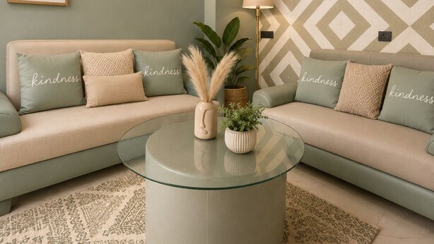 Uma sala de estar moderna com um sofá, uma mesa de centro de vidro e almofadas decorativas.