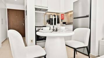 A modern kitchen with white appliances, a dining table with chairs, and a view of the adjacent living area.