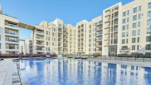 A residential building with multiple balconies, a swimming pool, and a clear sky. - Bloomfields Studio in Hayat Boulevard  (Dubai)