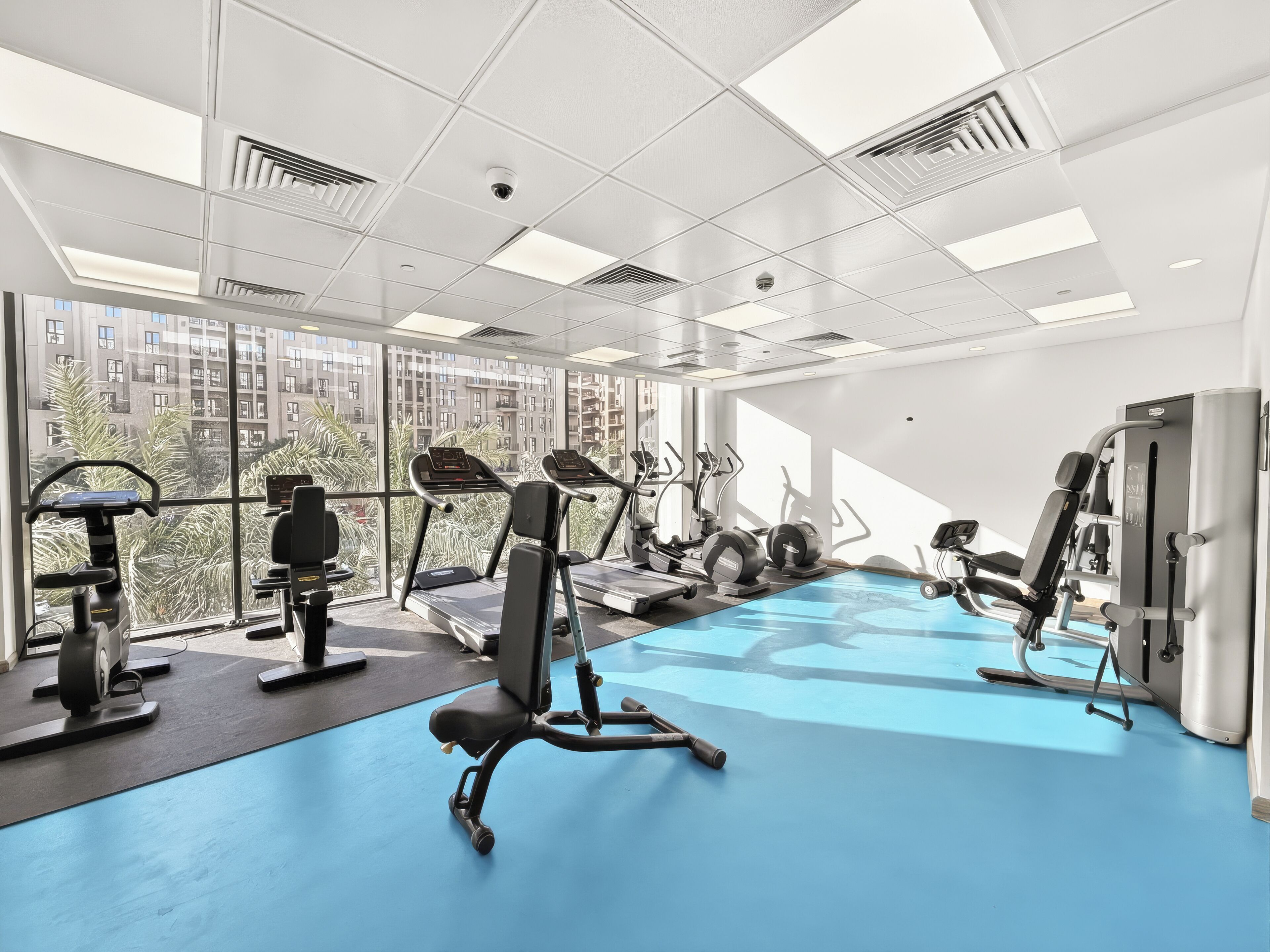 A modern gym with treadmills, elliptical machines, and weight equipment.