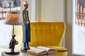 En gul sofa, en lampe og en figur på et bord.