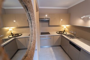 A modern kitchen with two sinks, a stove, and overhead lighting.