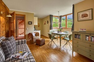 Una sala de estar acogedora con sofá, una mesa de comedor con sillas, una zona de cocina y vistas al exterior.