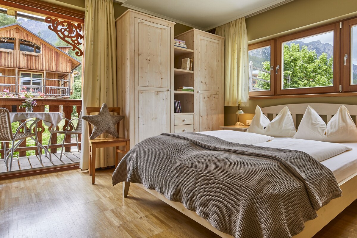 A bedroom with a bed, bedside tables, a wardrobe, and a view of the mountains.