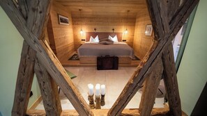 Ein Schlafzimmer in einer Holzhütte mit einem Bett, Nachttischlampen und einem kleinen Tisch.