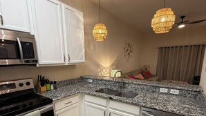 Eine moderne Küche mit weißen Schränken, Granit Arbeitsplatten, Edelstahlgeräten und zwei Hängeleuchtern.