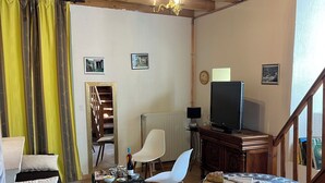 Ein gemütliches Wohnzimmer mit einer Couch, Sesseln, einem Couchtisch, einem Fernseher und einer Treppe.