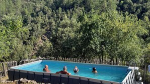 Ein Pool im Freien mit einem bewaldeten Hügel im Hintergrund.