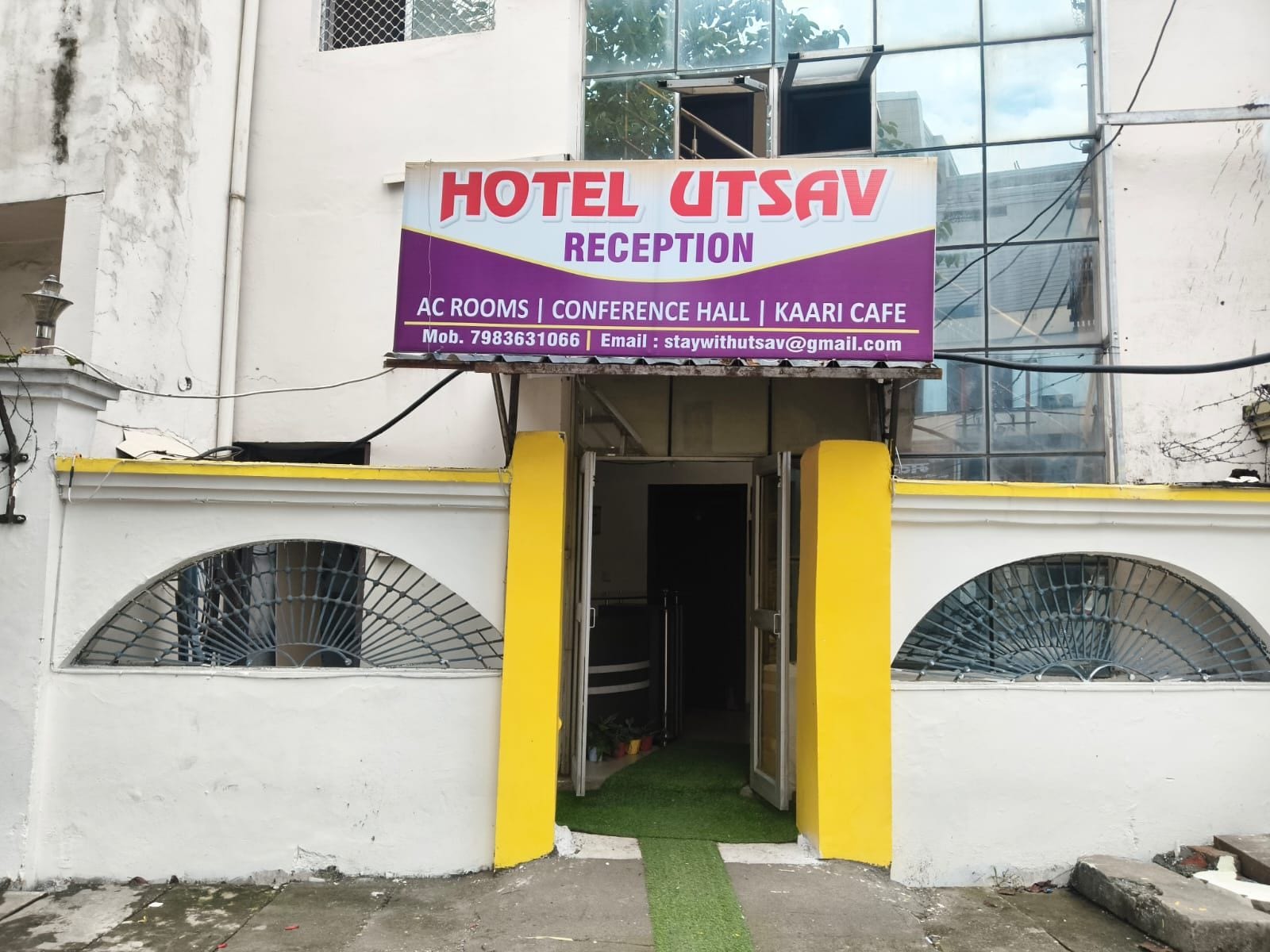 Una recepción de hotel con un cartel que indica servicios como habitaciones con aire acondicionado, salón de conferencias y café Kaari.