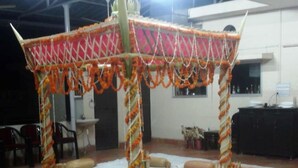 Una habitación con una estructura central decorada en naranja y blanco, rodeada de esteras blancas y cojines color beige.