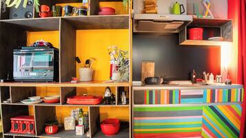 A kitchen with multiple shelves, a microwave, and various kitchen utensils.