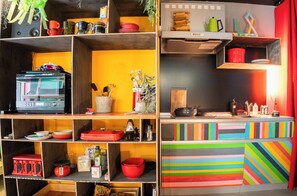 Una cocina con varias estanterías, un microondas y diversos utensilios de cocina.