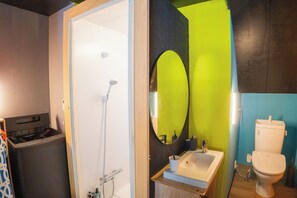 Et badeværelse med bruser, vask, toilet og vaskemaskine.