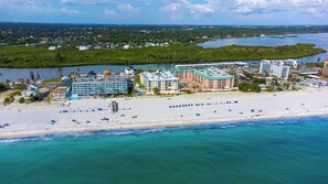 An aerial view of a coastal resort with beachfront hotels, a sandy beach, and a marina. - Treat Yourself to Breathtaking Beachfront Views in this Sunlit and Spacious Corner Gem! (Indian Shores)