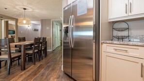 Una cocina moderna con un refrigerador de acero inoxidable, una mesa de comedor de madera y sillas.