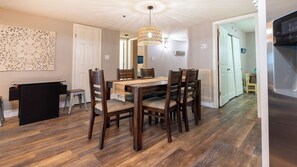 Ein Essbereich mit einem Holztisch und Stühlen, einer hängenden Leuchte und einer weißen Tür im Hintergrund.