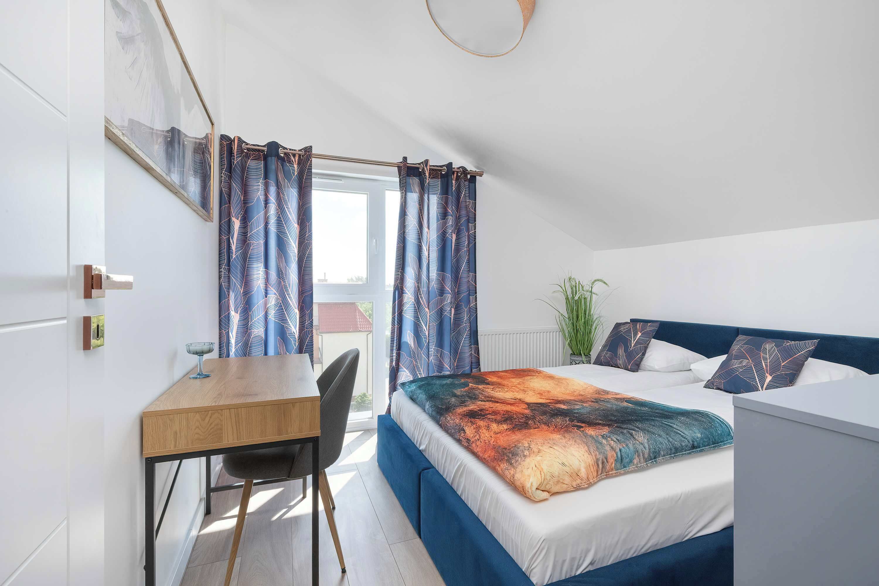 A bedroom with a bed, a desk, and a chair.