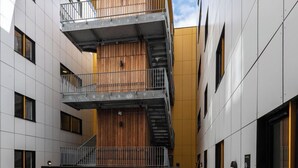 Ein mehrstöckiges Gebäude mit einem zentralen Atrium, Balkonen und einer Treppe.