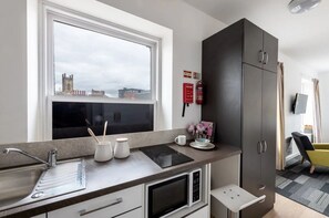 A modern kitchen with a window, a microwave, a sink, and a cabinet. - Student Only The Arch (Liverpool)