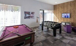 A pool table, foosball table, and a television screen in a room with wooden walls and a window with curtains. - Student Only The Arch (Liverpool)