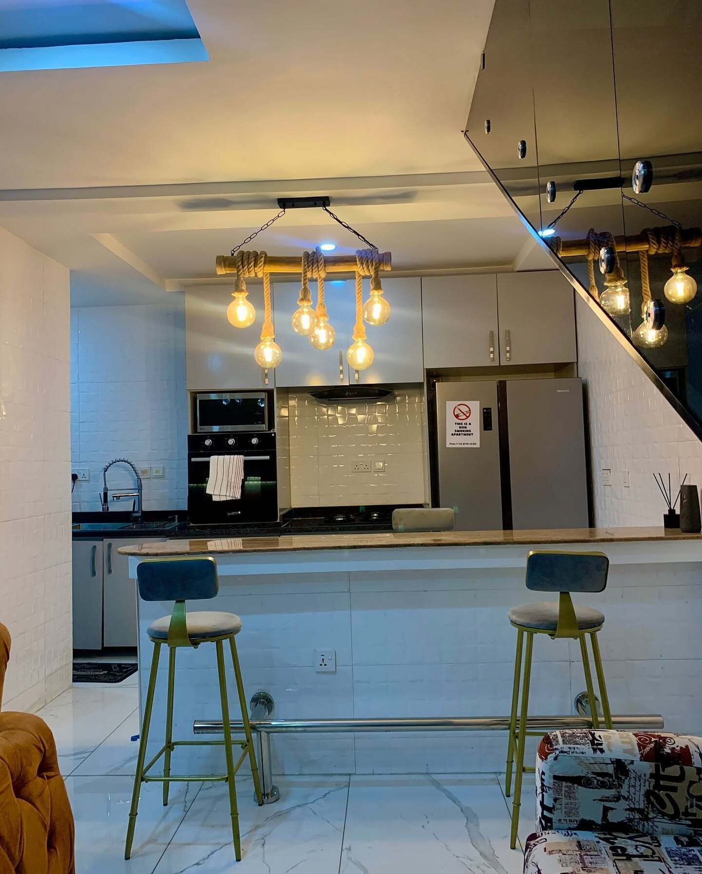 Una cucina moderna con un'isola centrale, elettrodomestici in acciaio inossidabile e un lampadario originale.