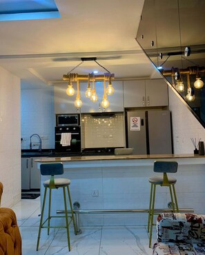 Una cocina moderna con una isla central, electrodomésticos de acero inoxidable y una lámpara original.
