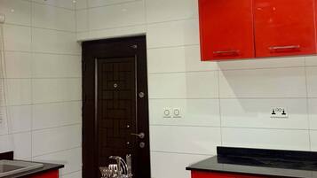 A kitchen with red cabinets, a black countertop, and blue pendant lights.