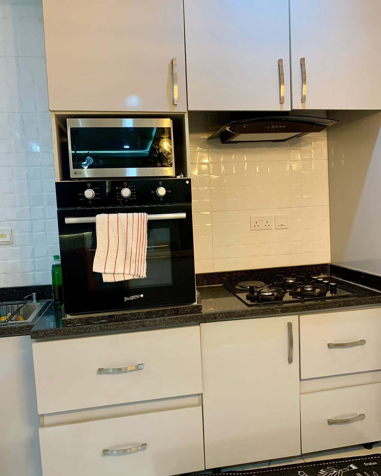 Une cuisine avec des meubles blancs, un four noir et une cuisinière à gaz.