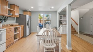 Una cocina con armarios de madera, un refrigerador, una mesa de comedor con sillas y vistas al exterior.