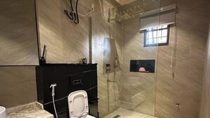 A modern bathroom with a glass-enclosed shower, a toilet, a sink, and a mirror. - Ocabique Planet Hotel (Port Harcourt)