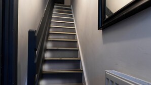 Un escalier avec une rampe, un radiateur et un cadre de porte.