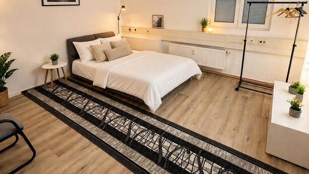 A bedroom with a bed, bedside tables, a radiator, a window, and a view of the outside.