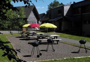 Un'area patio esterna con tavoli da picnic e barbecue.