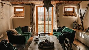 Ein rustikaler Raum mit zwei grünen Sofas, einem Holztisch und einem großen Fenster mit Blick auf ein Feld.