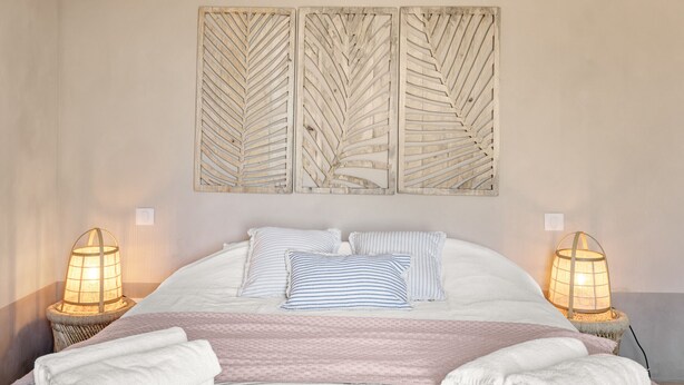 A neatly made bed with striped pillows, a pink blanket, and two bedside lamps. - Mas des Cigales – Pool & Saint-Paul views (Vence)