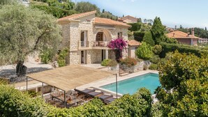 A stone villa with a swimming pool, outdoor furniture, and lush greenery. - Mas des Cigales – Pool & Saint-Paul views (Vence)