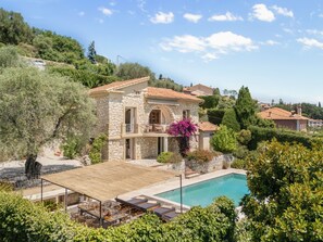 A stone villa with a swimming pool, outdoor furniture, and lush greenery. - Mas des Cigales – Pool & Saint-Paul views (Vence)