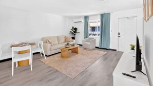Una sala de estar moderna con un sofá, una mesa de centro y un mueble para televisión.
