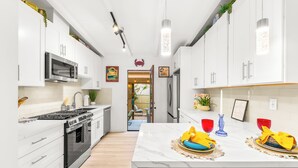 A modern kitchen with white cabinets, stainless steel appliances, and a marble island. - Walk To Beach and Village W/Jacuzzi & Firepit W/Great Reviews! (San Diego)