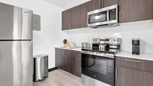 A modern kitchen with stainless steel appliances, dark wooden cabinets, and a white countertop. - Comfortable 2BR Near Beach & Cruise Port (Fort Lauderdale)