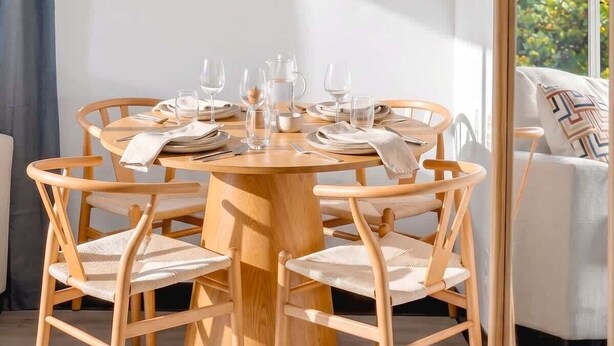 A round wooden dining table with six chairs, a mirror, and a view of greenery outside. - Comfortable 2BR Near Beach & Cruise Port (Fort Lauderdale)