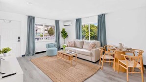 A modern living room with a sofa, coffee table, and dining table with chairs. - Comfortable 2BR Near Beach & Cruise Port (Fort Lauderdale)