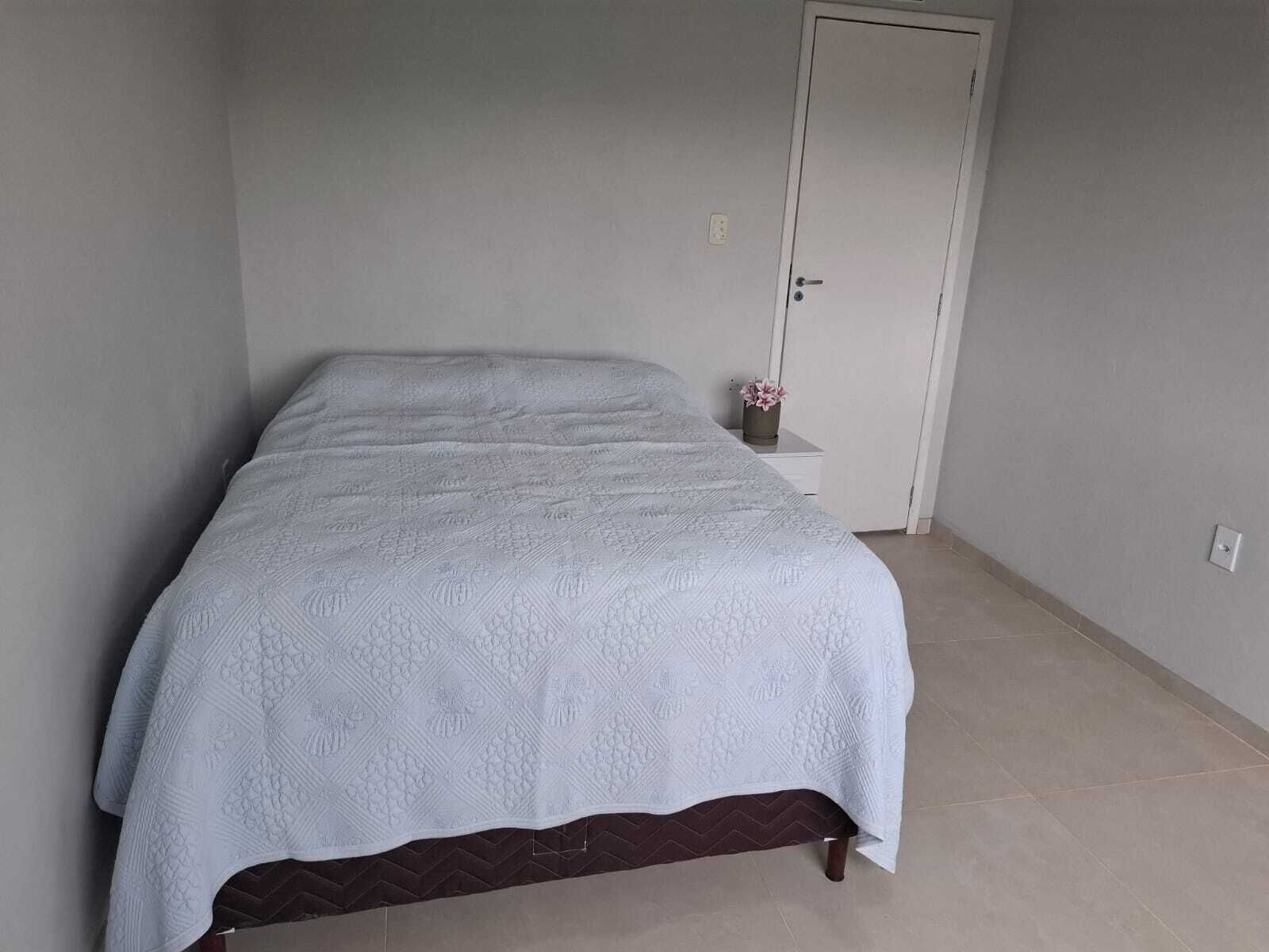 Un dormitorio con cama, mesita de noche, una puerta y toma de corriente.