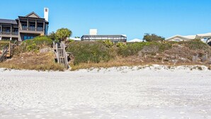 A beachfront property with a modern house, a covered walkway, and a sandy beach. - 5BR Gulf-Front Home with Private Beach & Heated Pool ~ Sleeps 12 (Seacrest)