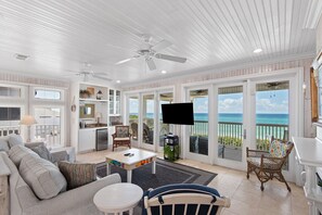 A spacious living room with a television, seating area, and a view of the ocean. - 5BR Gulf-Front Home with Private Beach & Heated Pool ~ Sleeps 12 (Seacrest)